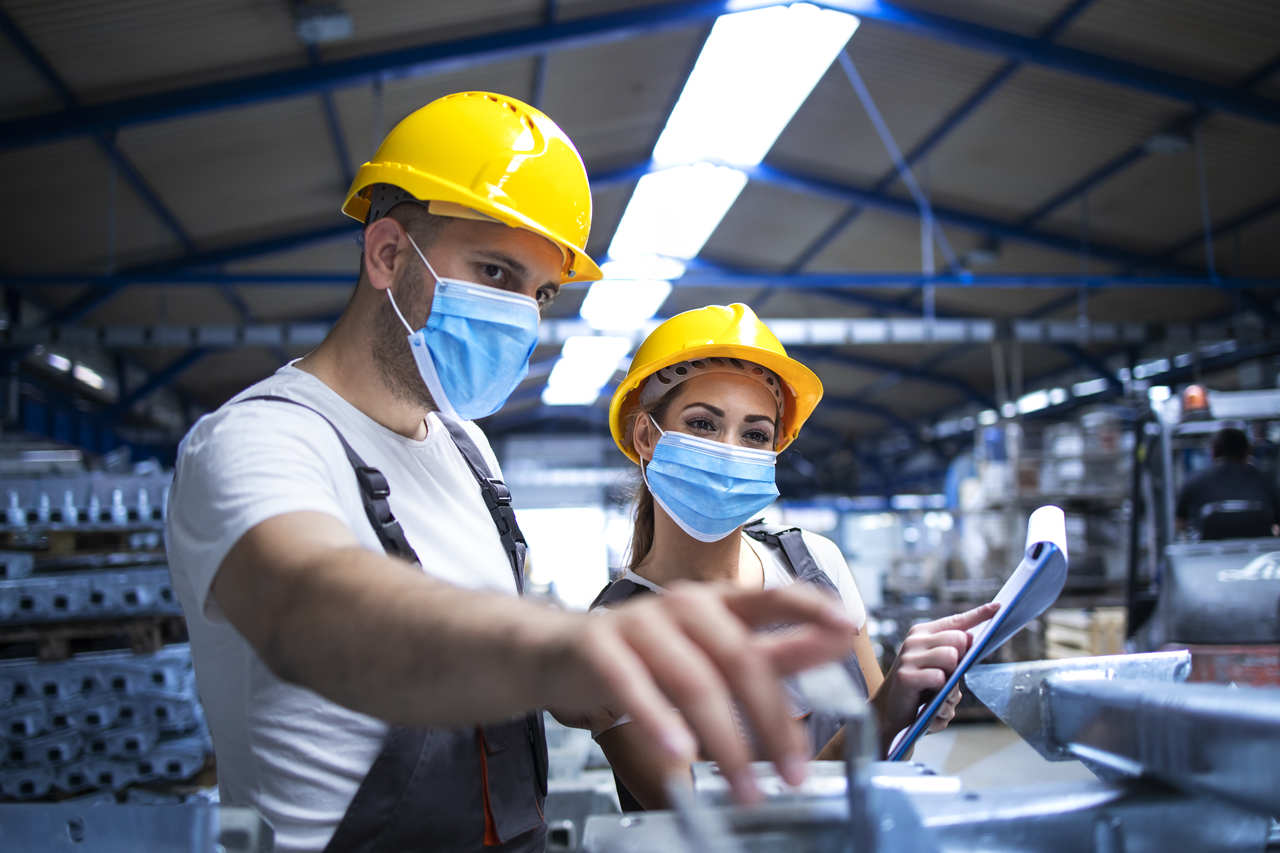 engenharia-de-producao-ead- homem e mulher de capacetes amarelos conversam em fábrica
